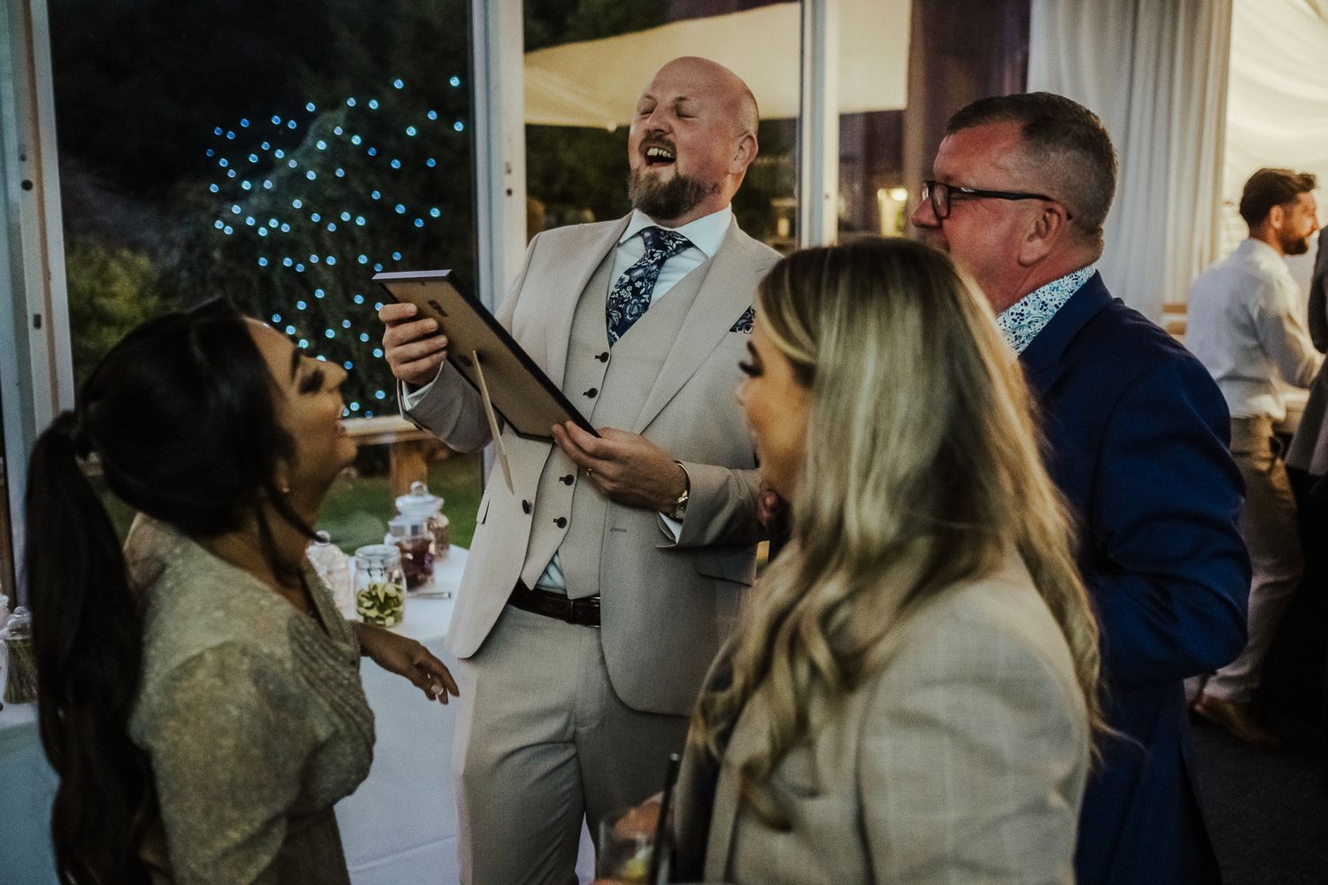 A group of people share an animated moment of laughter and conversation at an indoor social gathering.