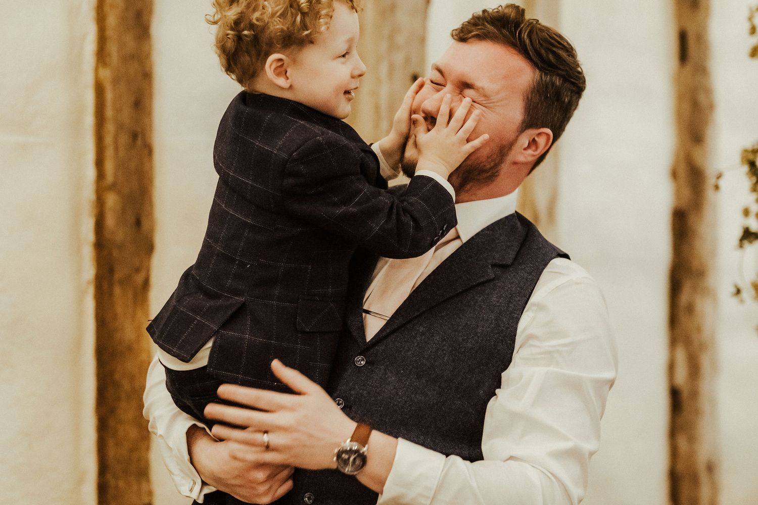 Playful moment between toddler and adult in formal wear.