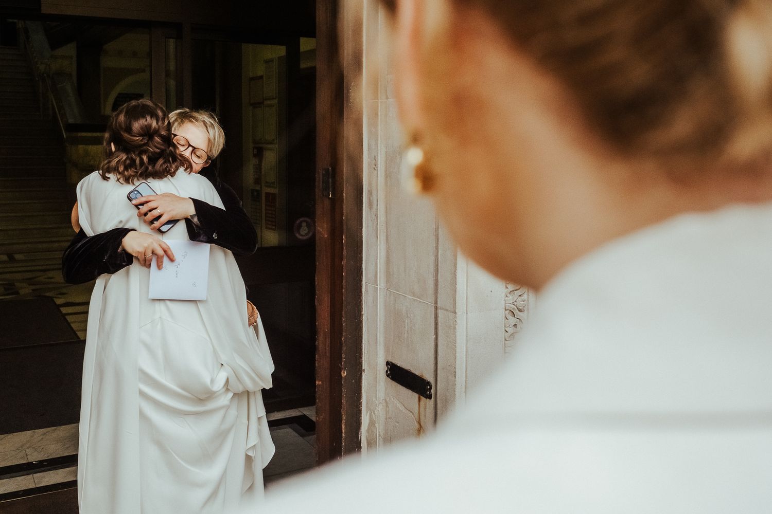 Intimate wedding embrace captured in a doorway with soft natural lighting.