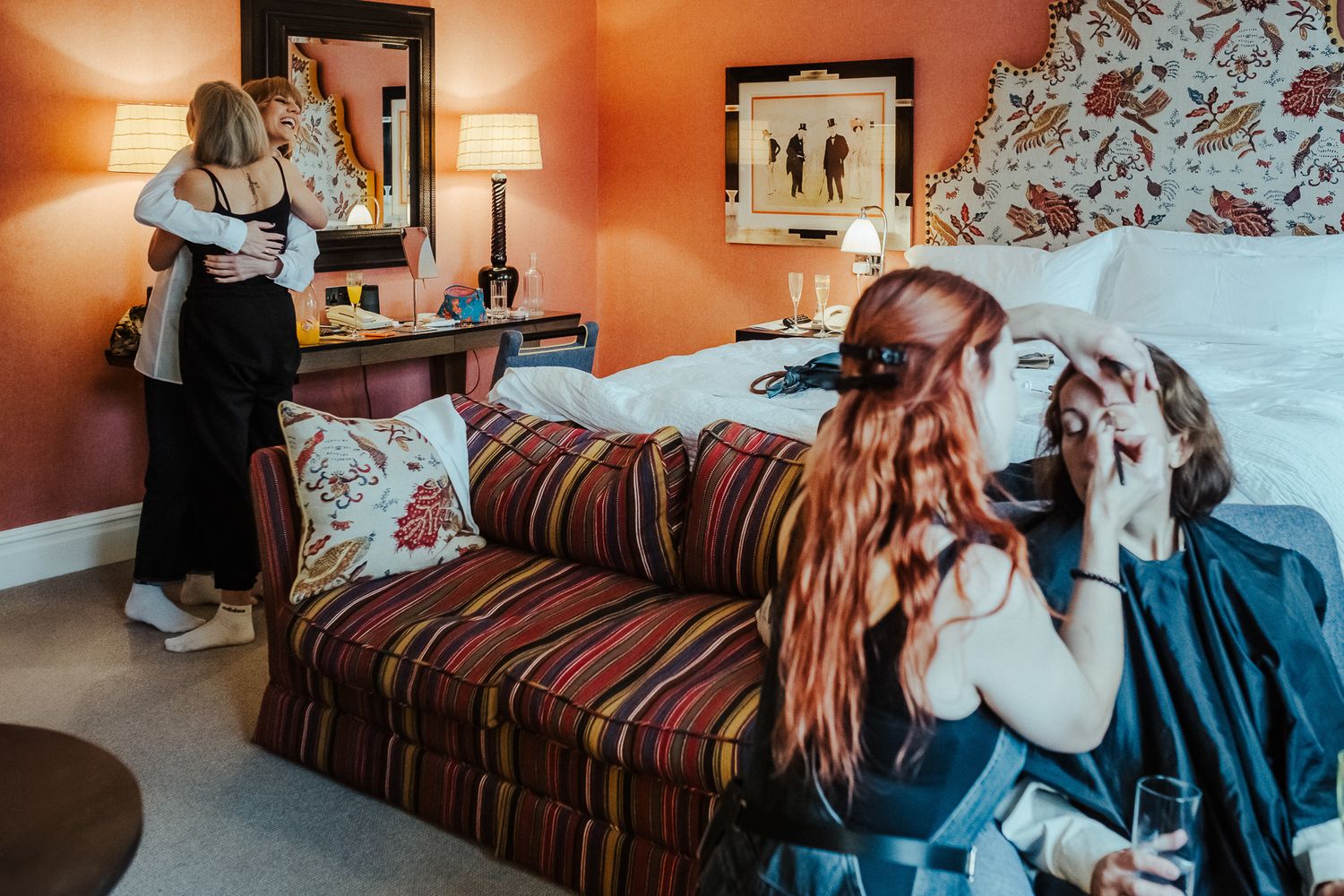 Group getting ready in a coral-colored room with a striped couch and floral wallpaper.