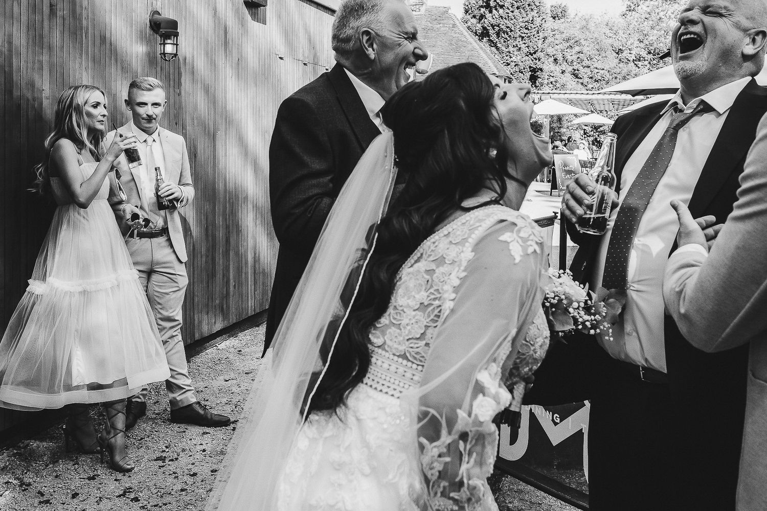 Black and white photo captures joyful laughter during wedding celebrations.