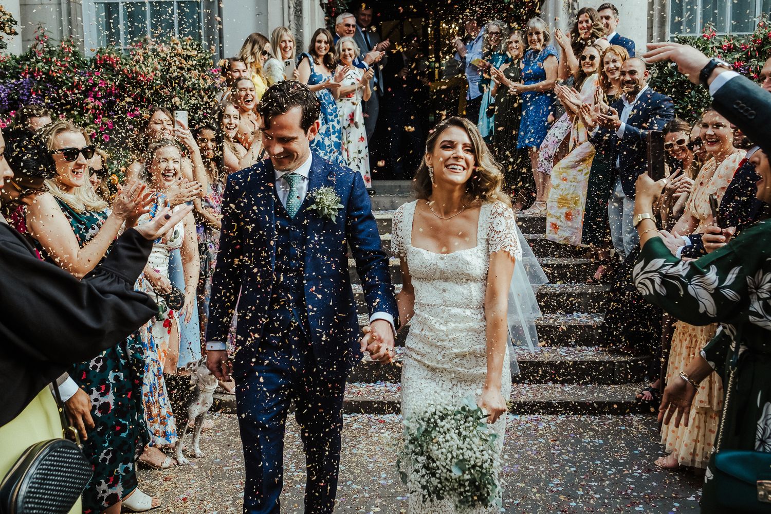 Newlyweds exiting church while guests shower them with confetti in celebration.