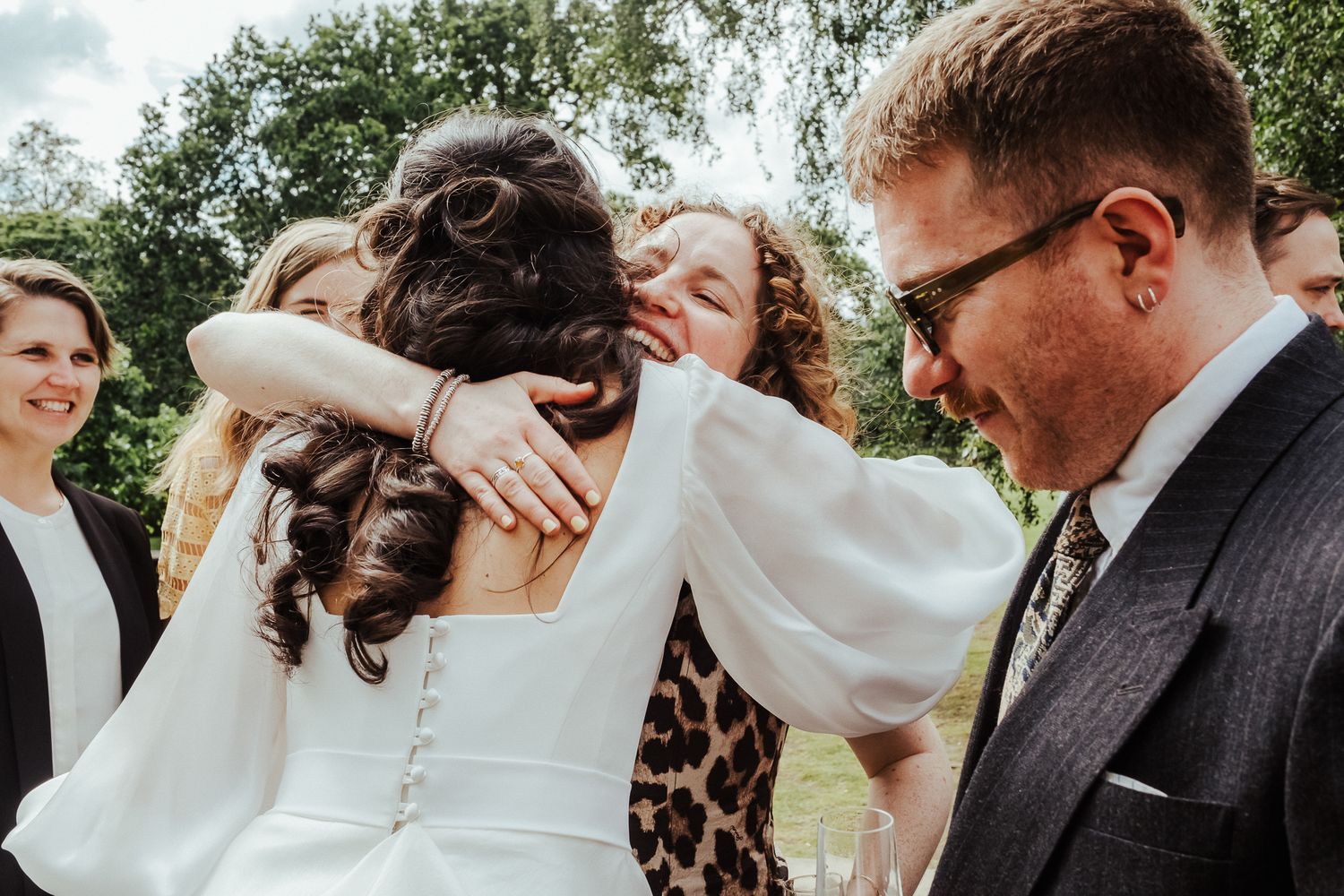 Candid moments of wedding guests celebrating outdoors with drinks.