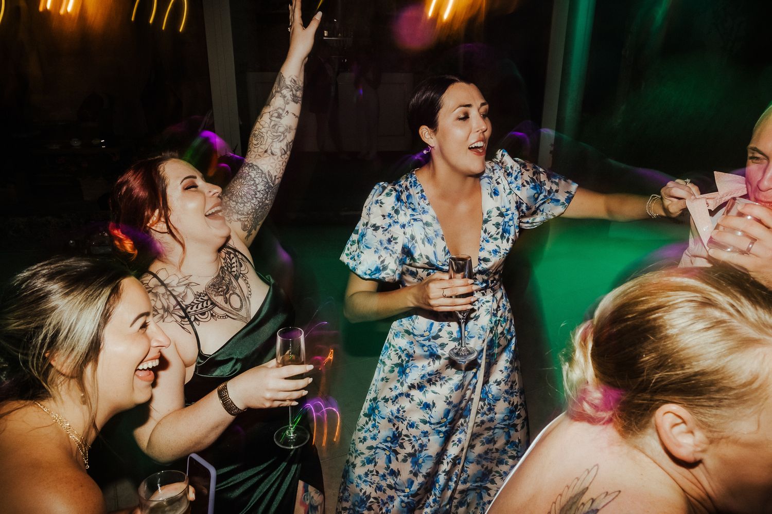 Wedding reception party guests dancing and celebrating with drinks in hand.