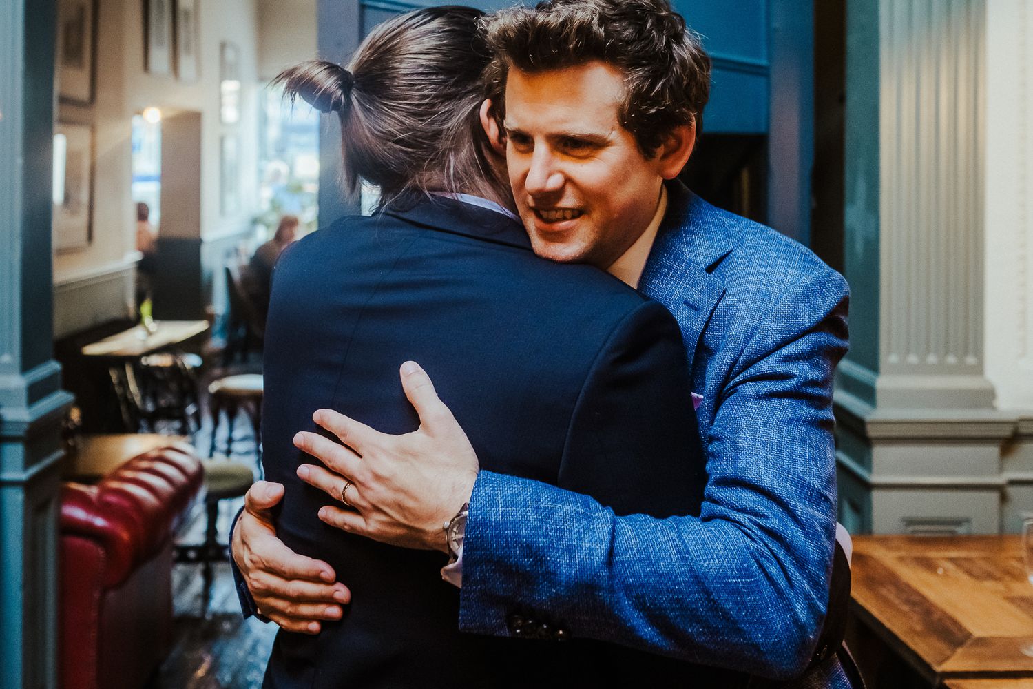 Two figures sharing an emotional embrace in formal attire.