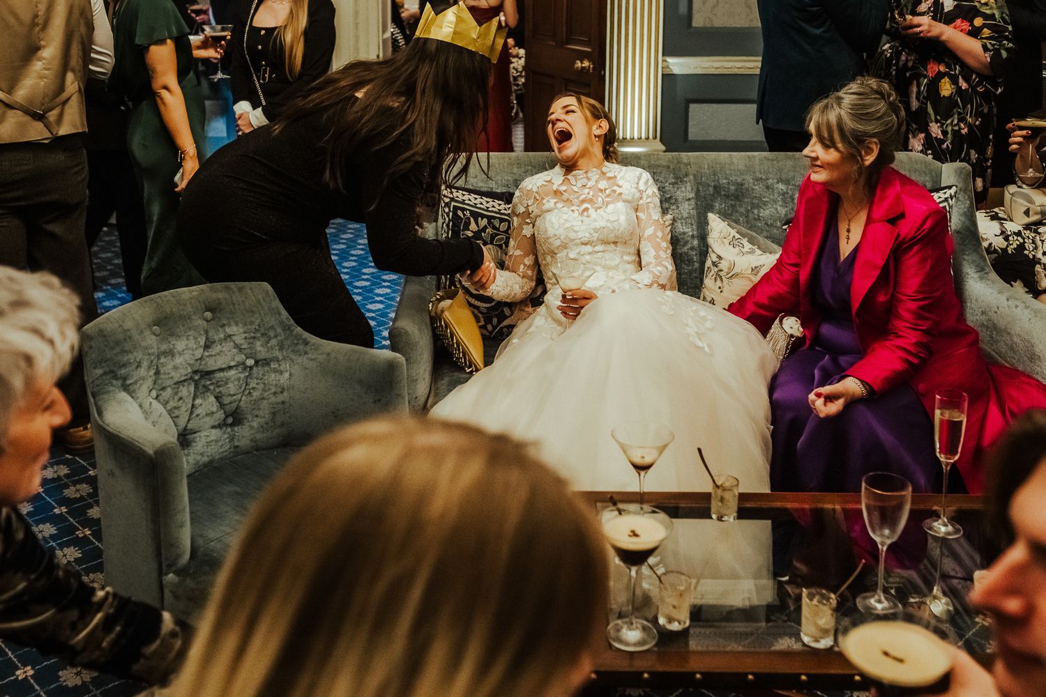 Wedding guests celebrate with champagne and laughter at an elegant indoor reception.