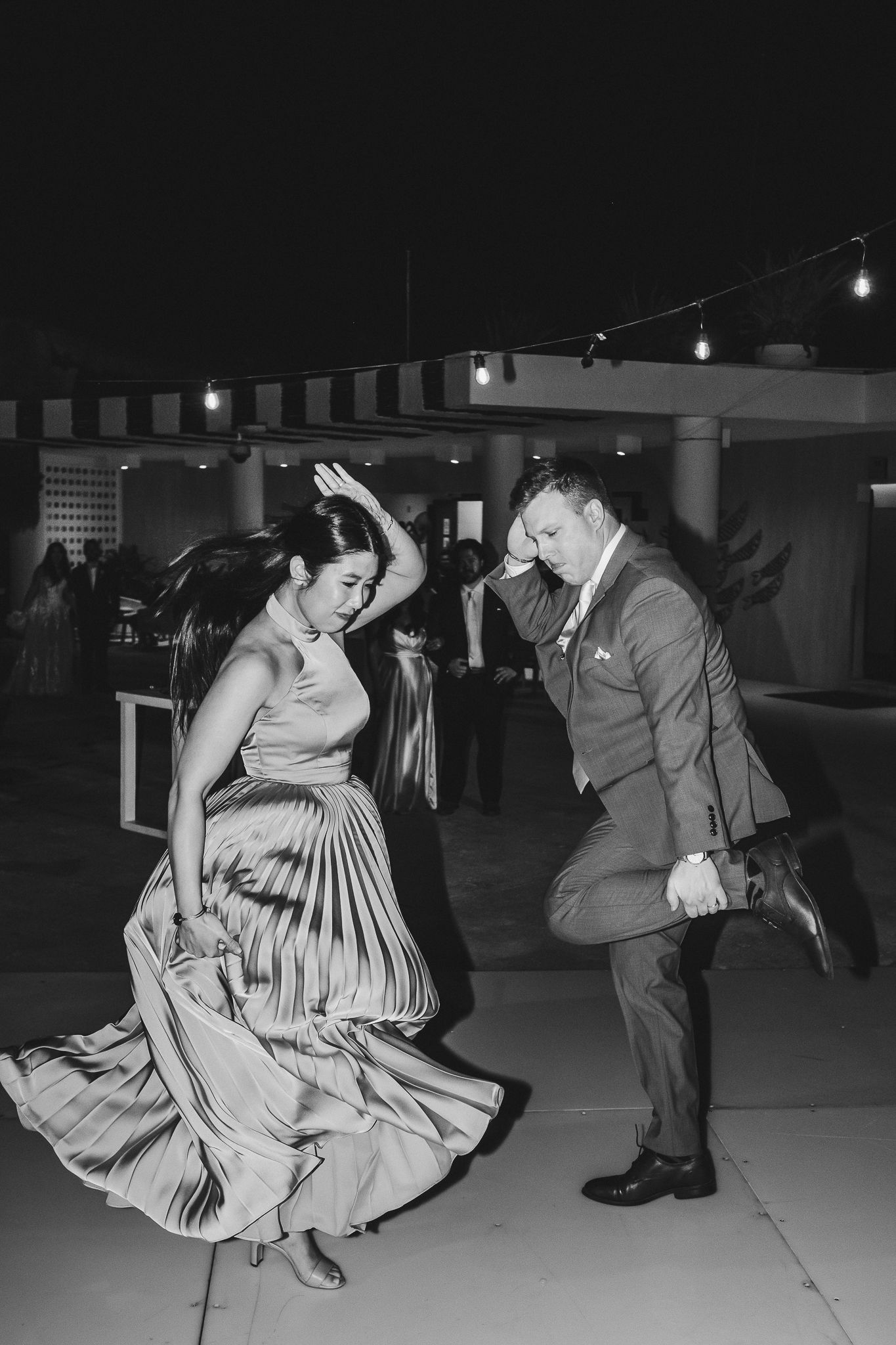 A lively dance moment captured in black and white at an evening celebration.