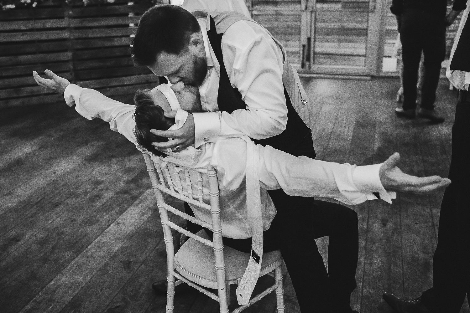 Black and white photo of couple performing dramatic dip dance move on wooden floor.