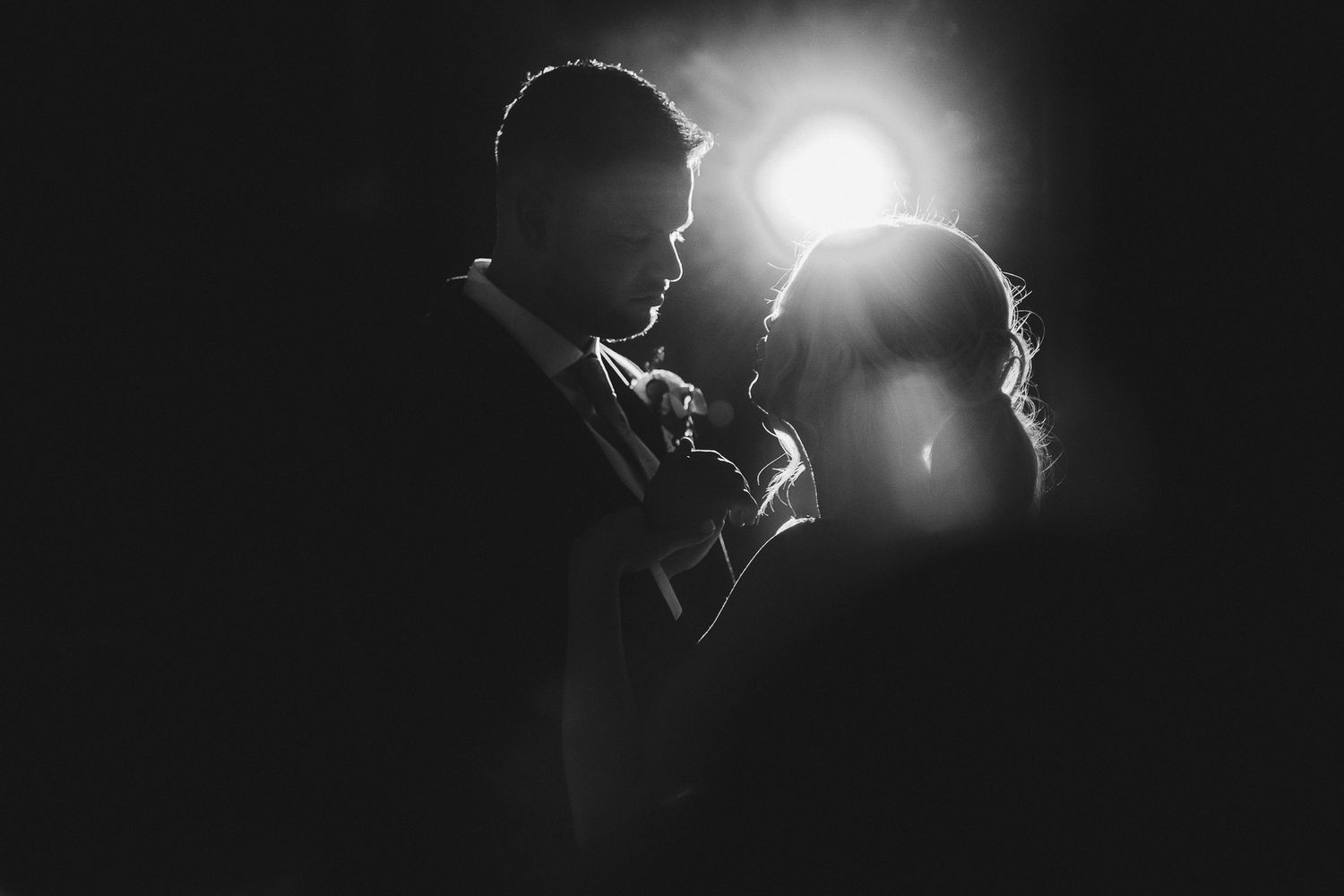 Dramatic silhouette of a couple in an intimate moment with backlighting creating a romantic atmosphere.