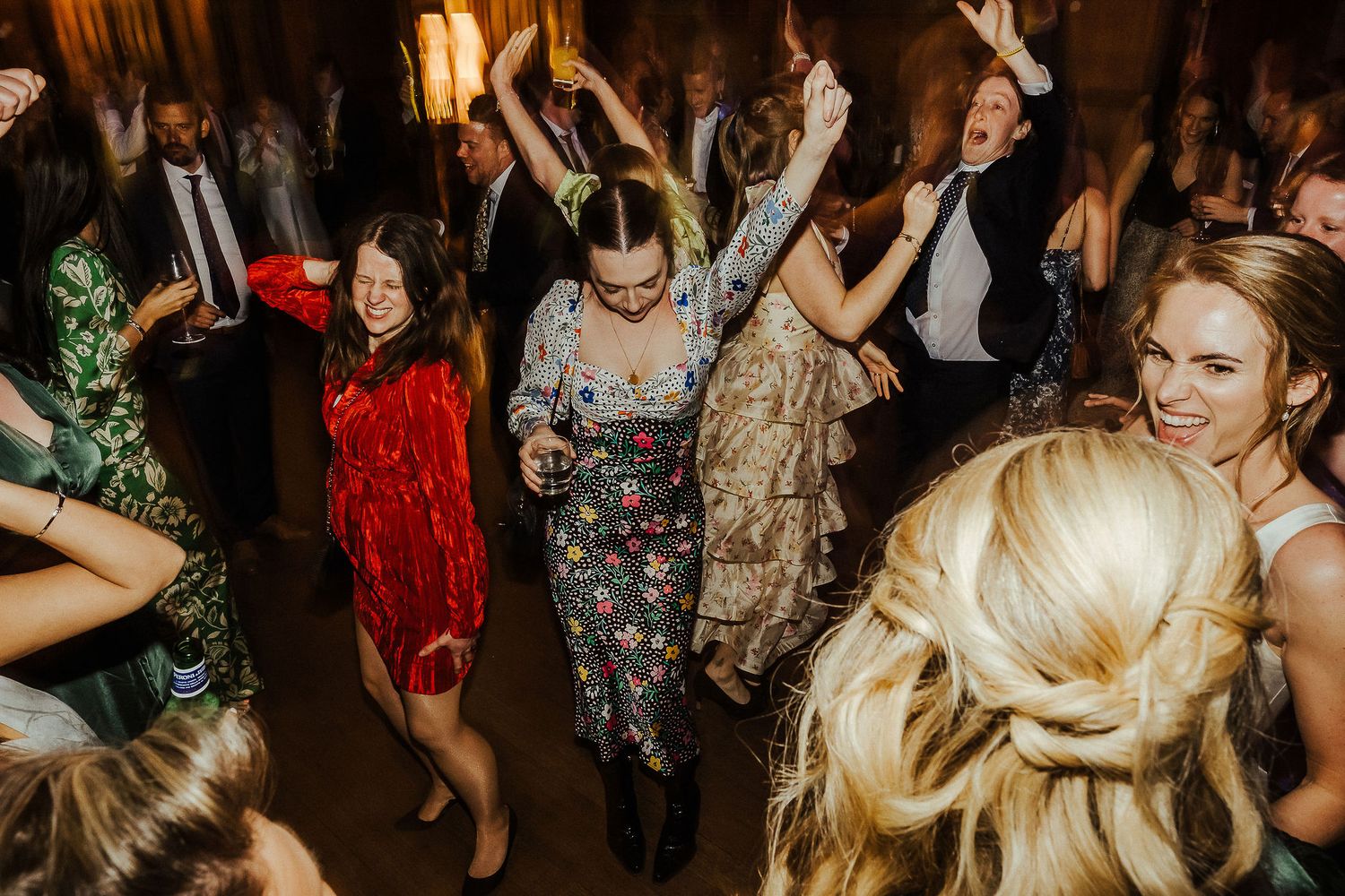 Wedding reception dance party with guests celebrating enthusiastically in formal attire.