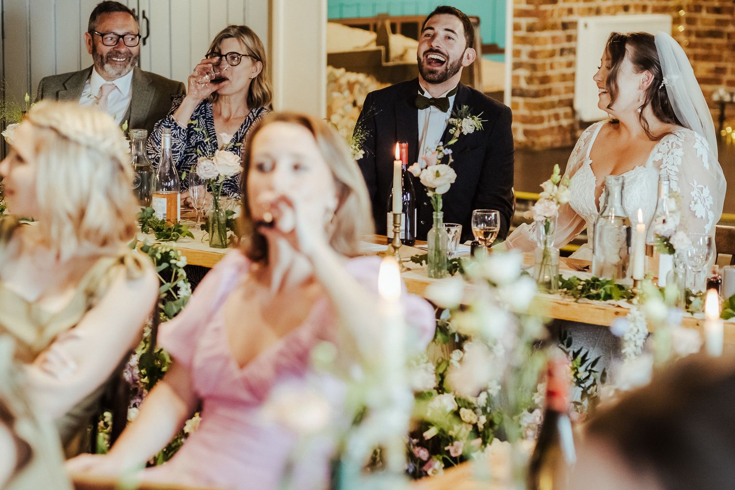 Candid reception photo capturing guests' laughter and joy during dinner speeches.