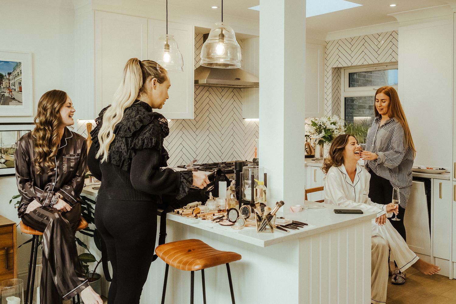 Group of people gathered in a modern white kitchen for a social event.
