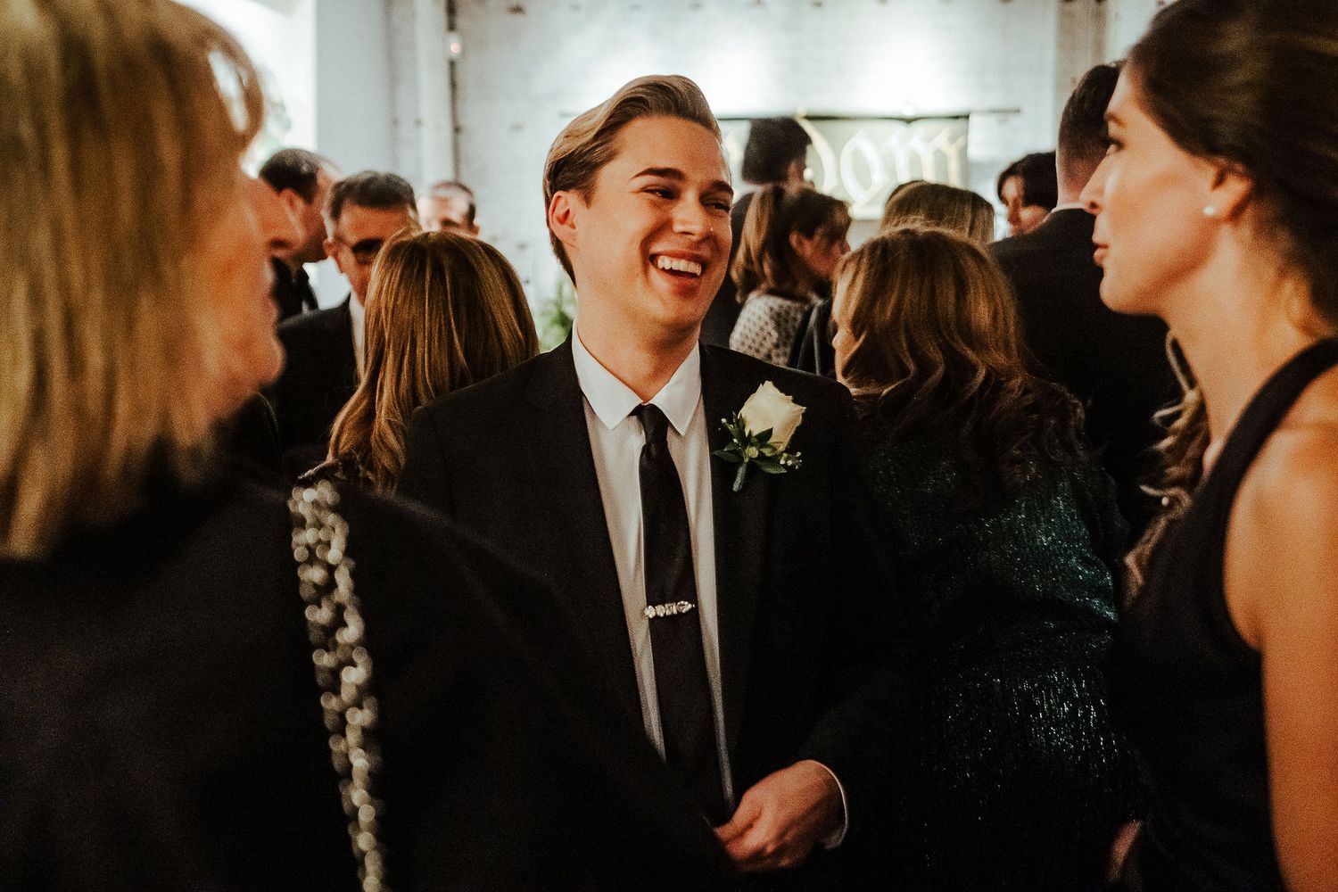 Wedding guests laughing and mingling at an indoor reception gathering.