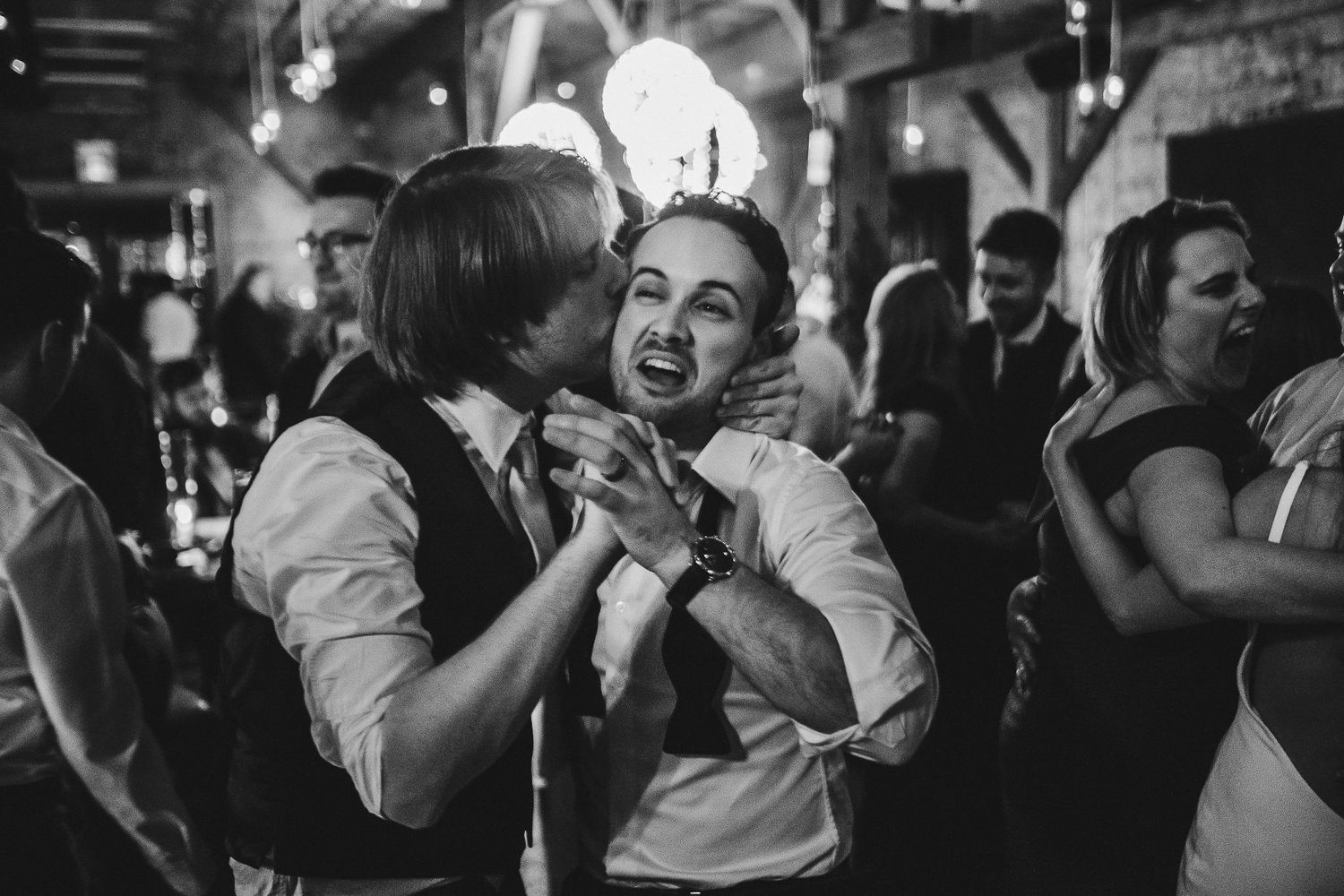 Two guests sharing an intimate dance moment at dimly lit wedding reception.