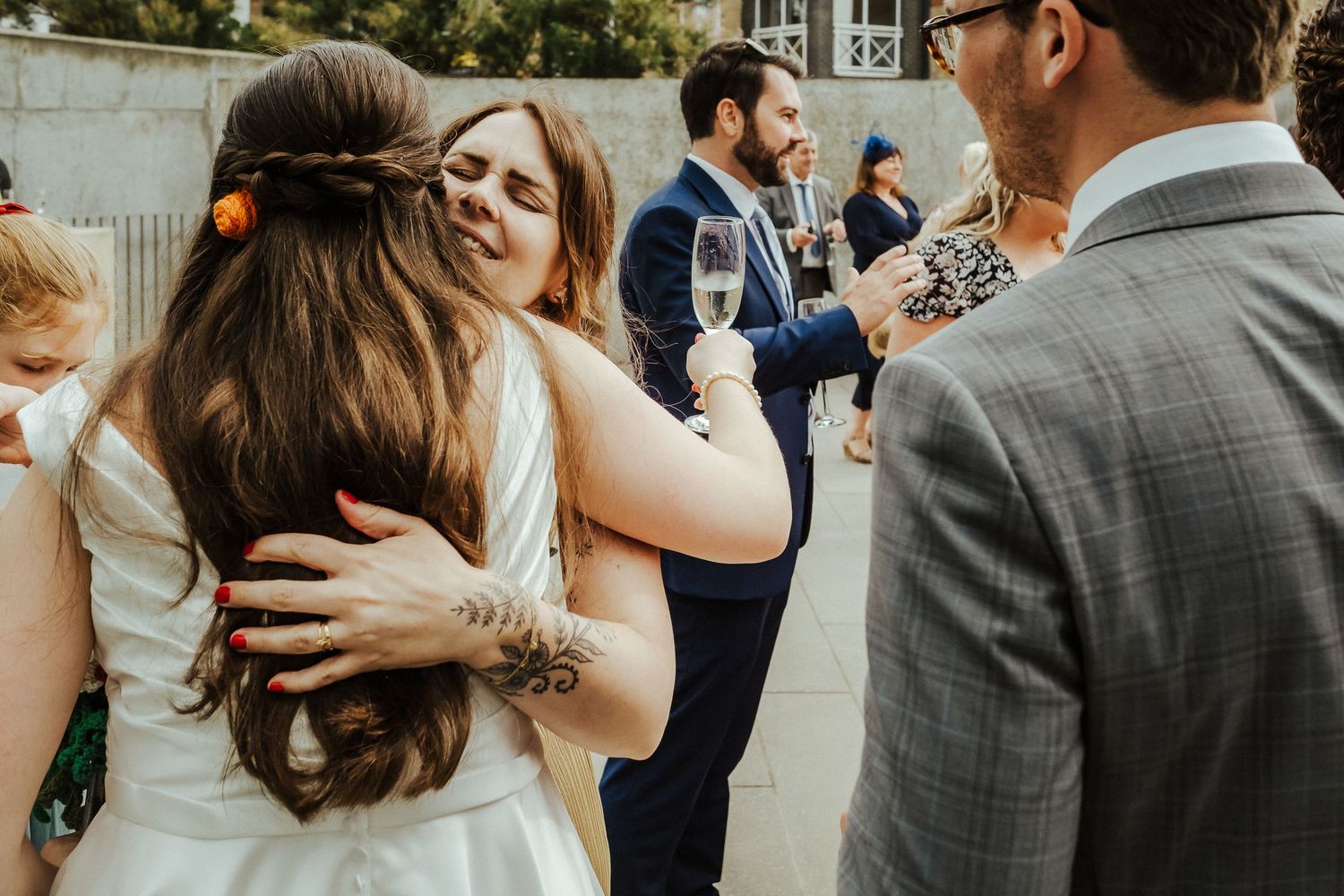 Guests share heartfelt embraces during an outdoor wedding reception.