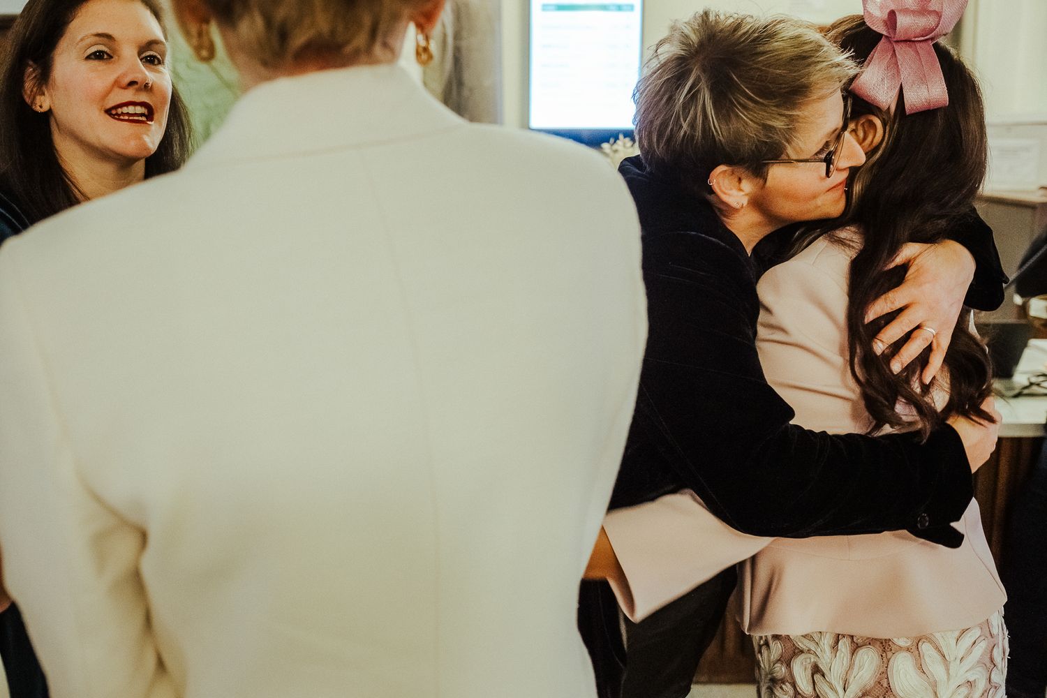 Candid wedding moment showing guests embracing and interacting during celebration.