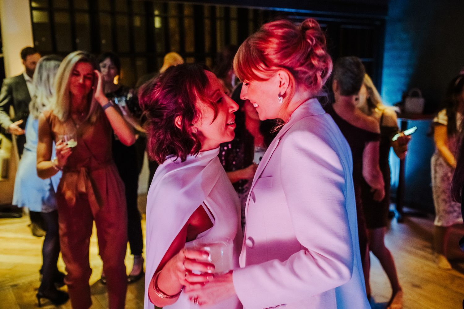 Wedding party dancing together with festive pink and purple lighting.