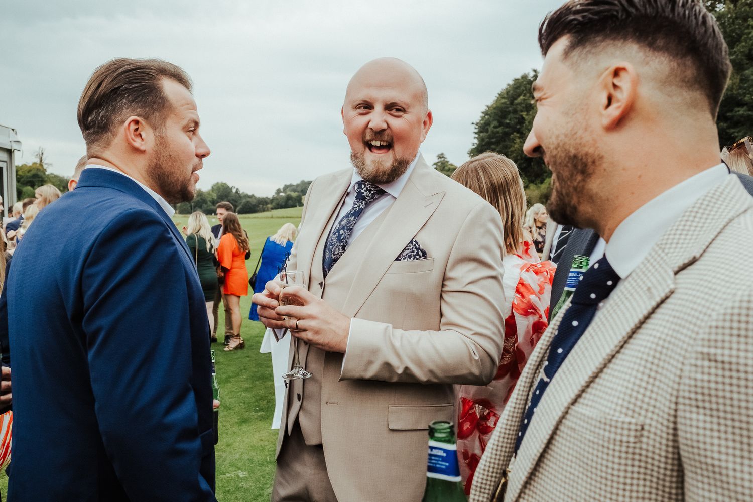 Guests celebrate and laugh together during an outdoor social gathering in formal attire.