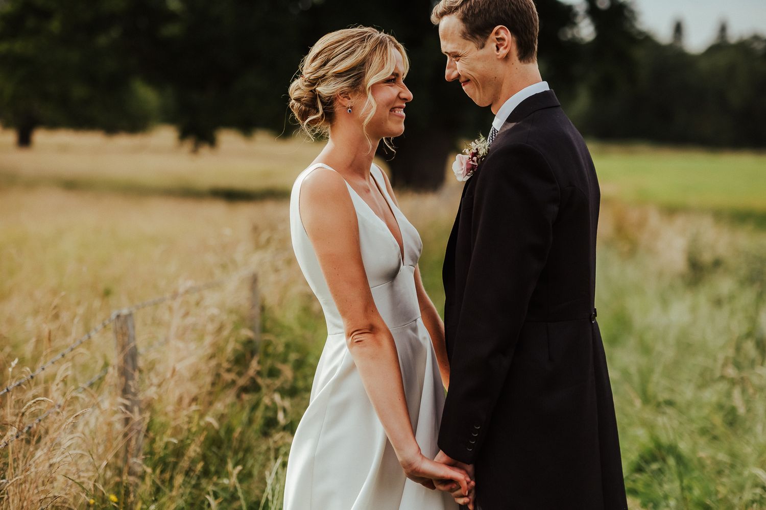 A couple shares an intimate moment while holding hands in a golden field.