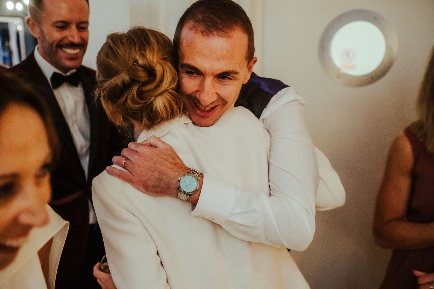 Wedding guests share warm embraces during an intimate celebration.