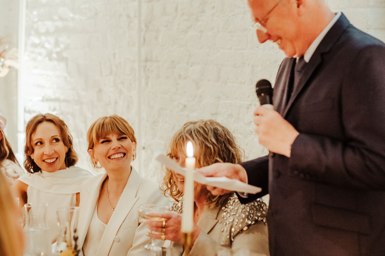 Wedding guests engage in lively conversation during a sunlit reception celebration.