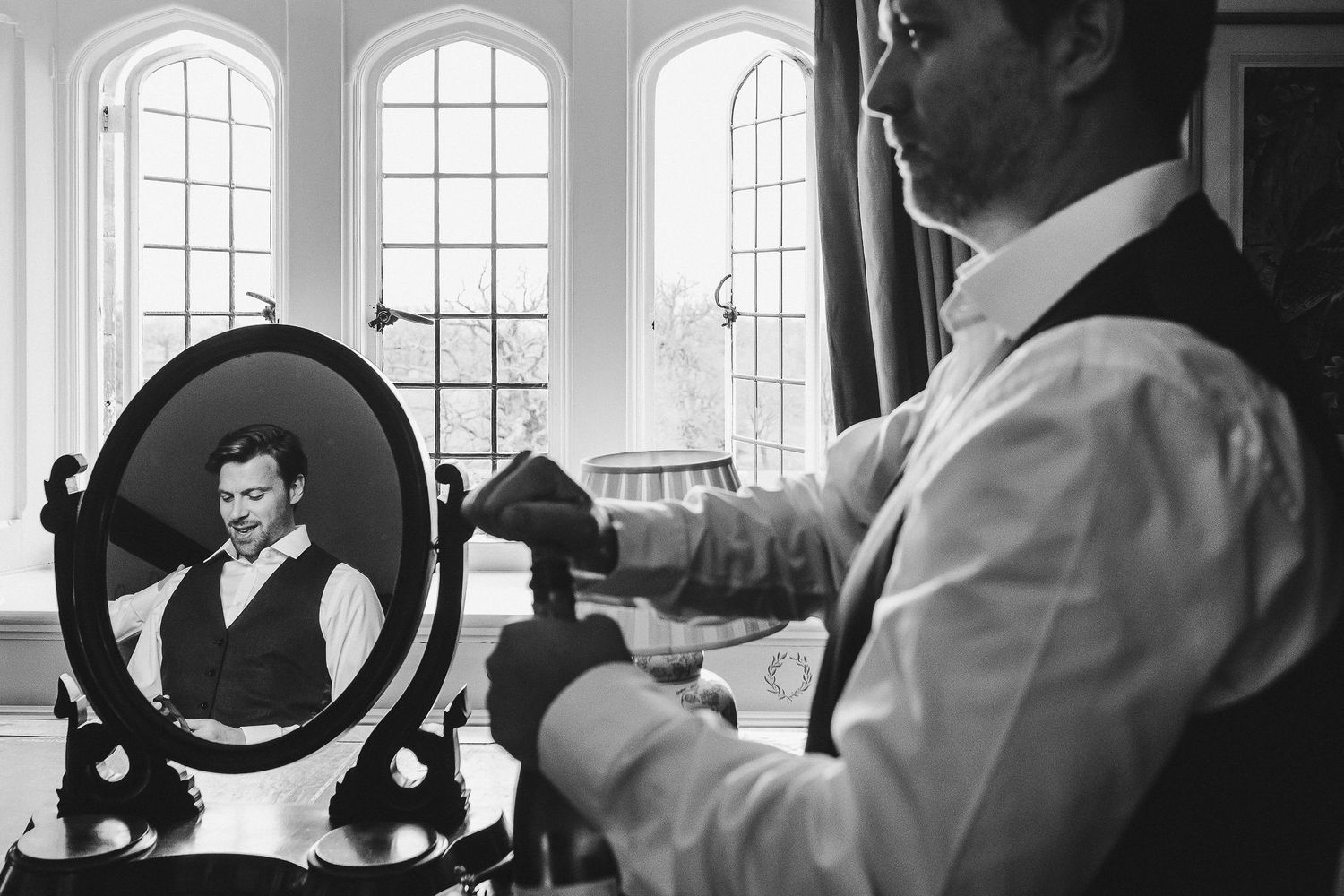 Black and white photo of morning preparation scene with vintage mirror and natural light.