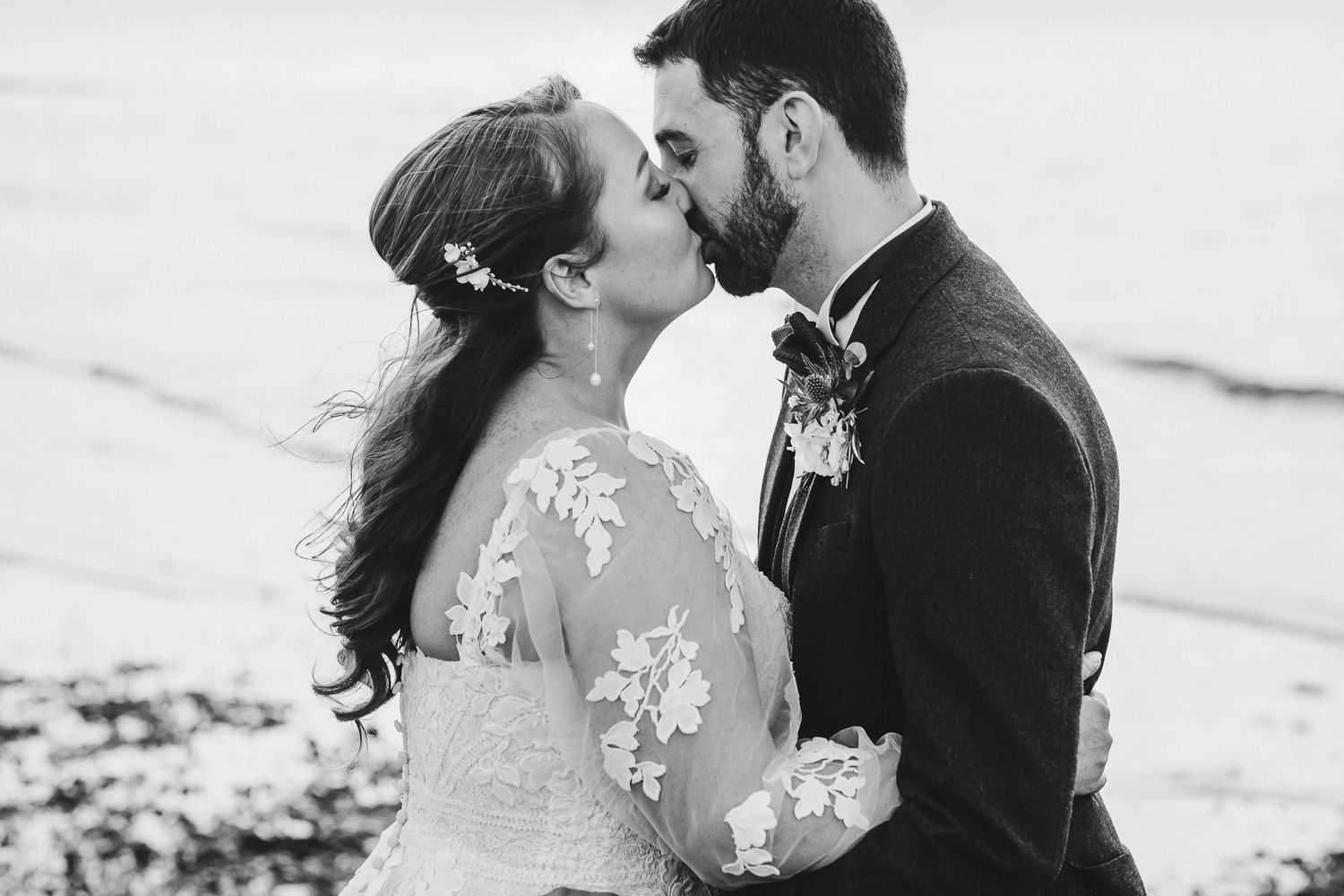 Black and white romantic beach portrait of couple in wedding attire.