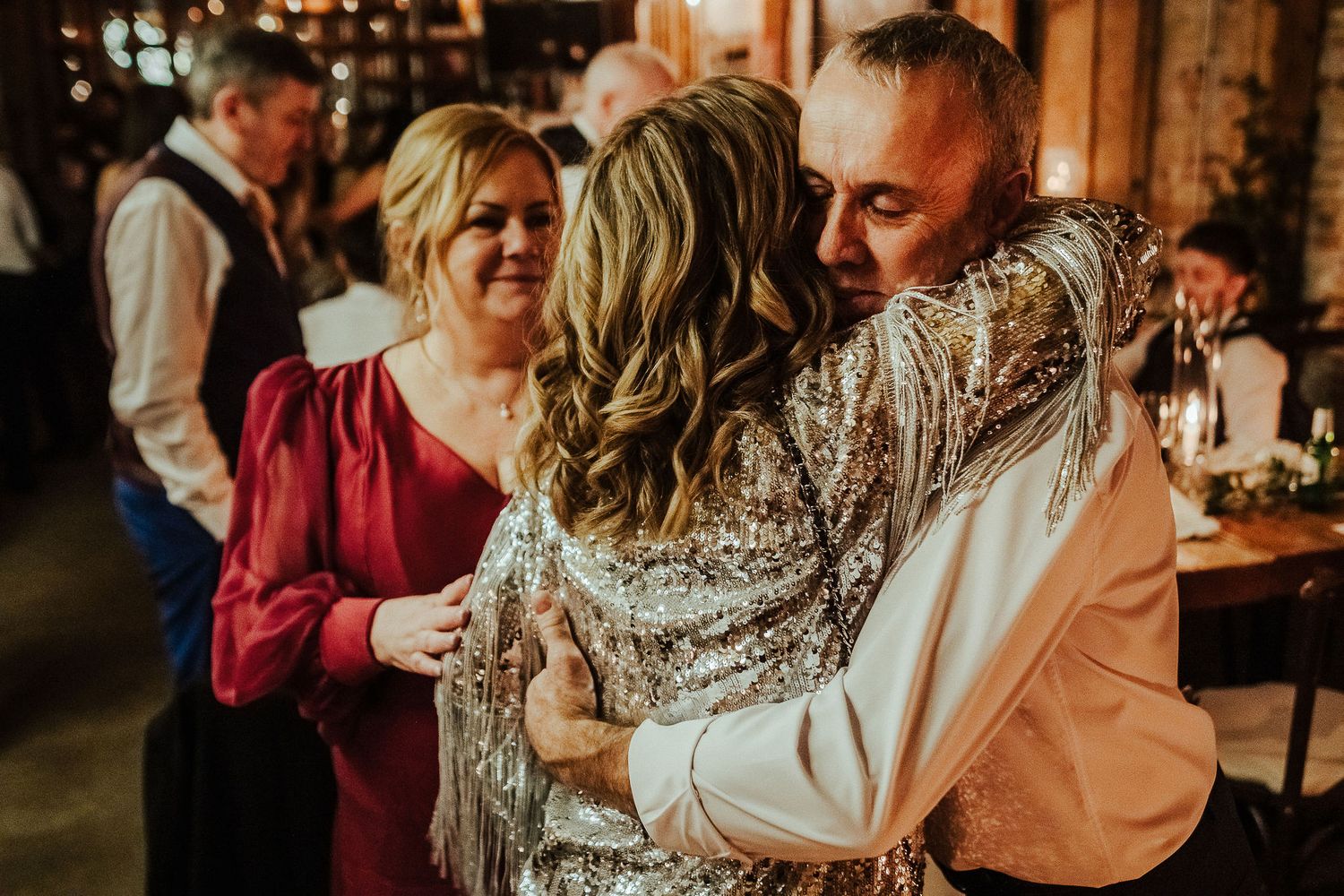 Emotional dance moment at a celebration with warm lighting and sparkly formal attire.