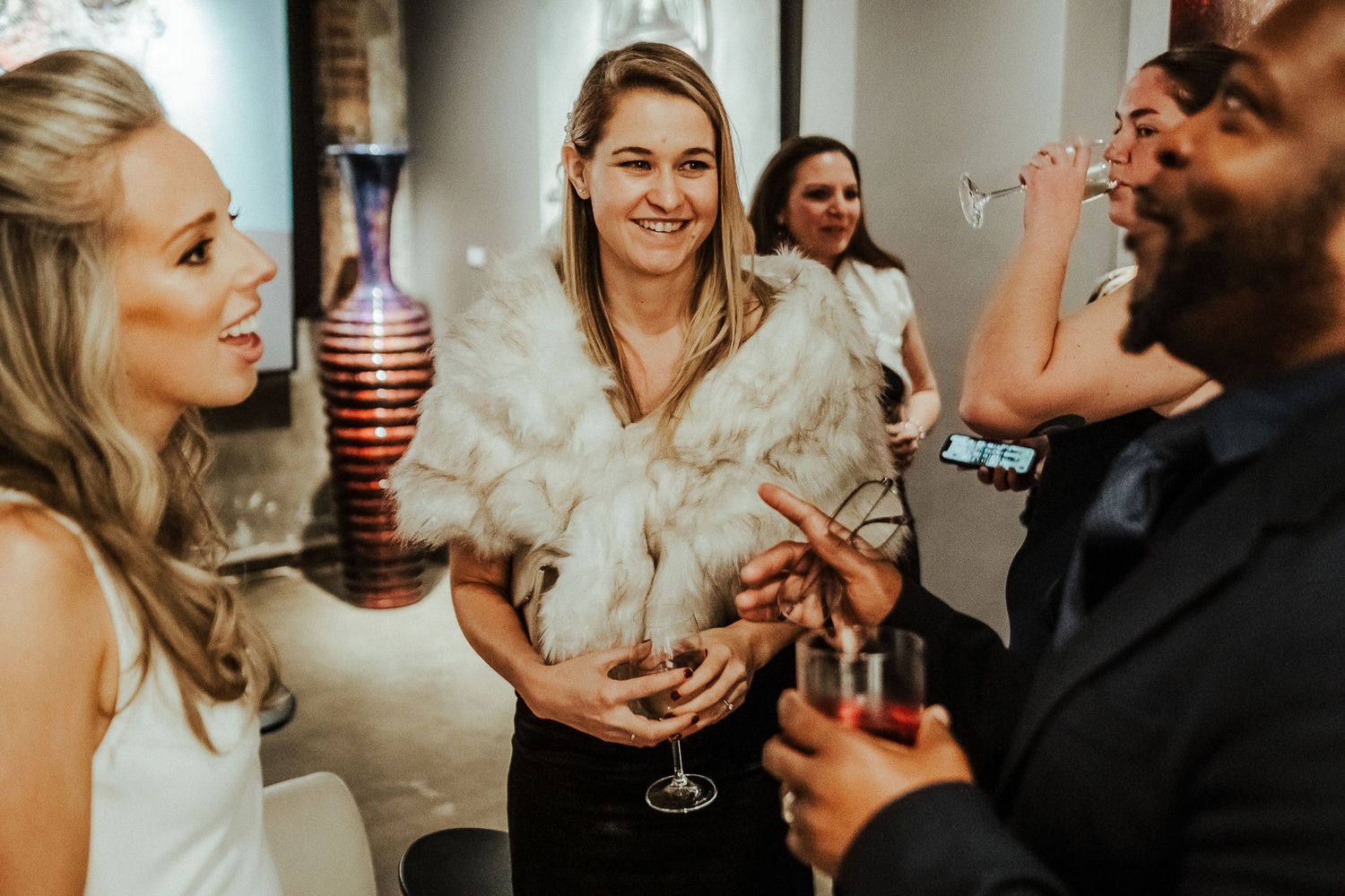 Wedding reception guests enjoying drinks and conversation in elegant venue setting.