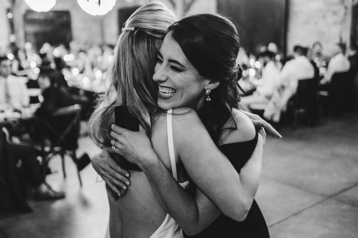 Two people embrace joyfully during a celebration in a black and white photograph.
