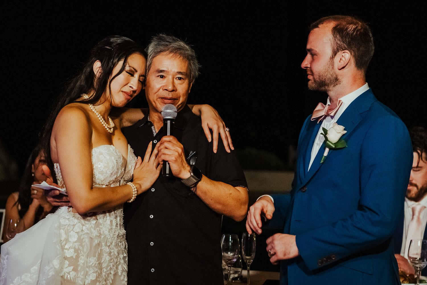 Emotional moment during wedding speeches at an evening outdoor reception.