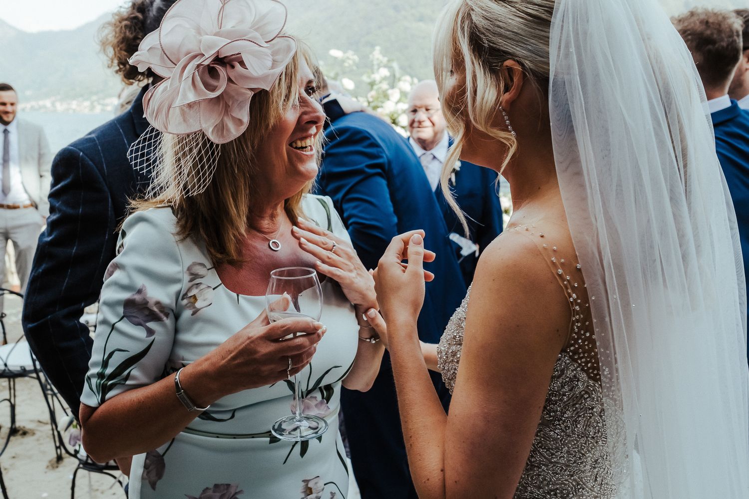 Wedding guests share an emotional moment during an outdoor reception by the water.