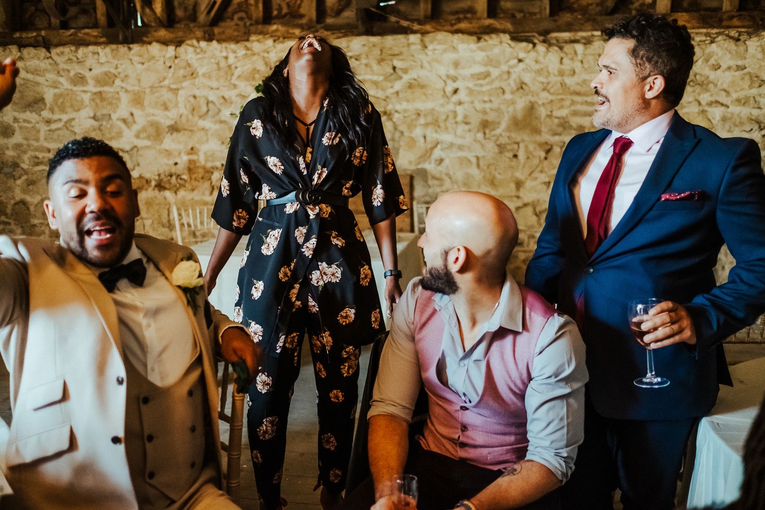 Wedding guests enjoying conversation against a rustic stone wall backdrop.