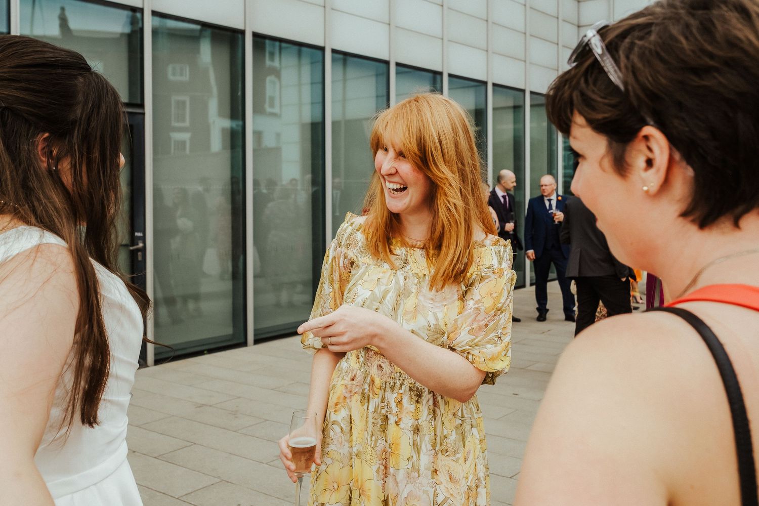 Guests in casual attire having animated conversation at outdoor wedding reception.