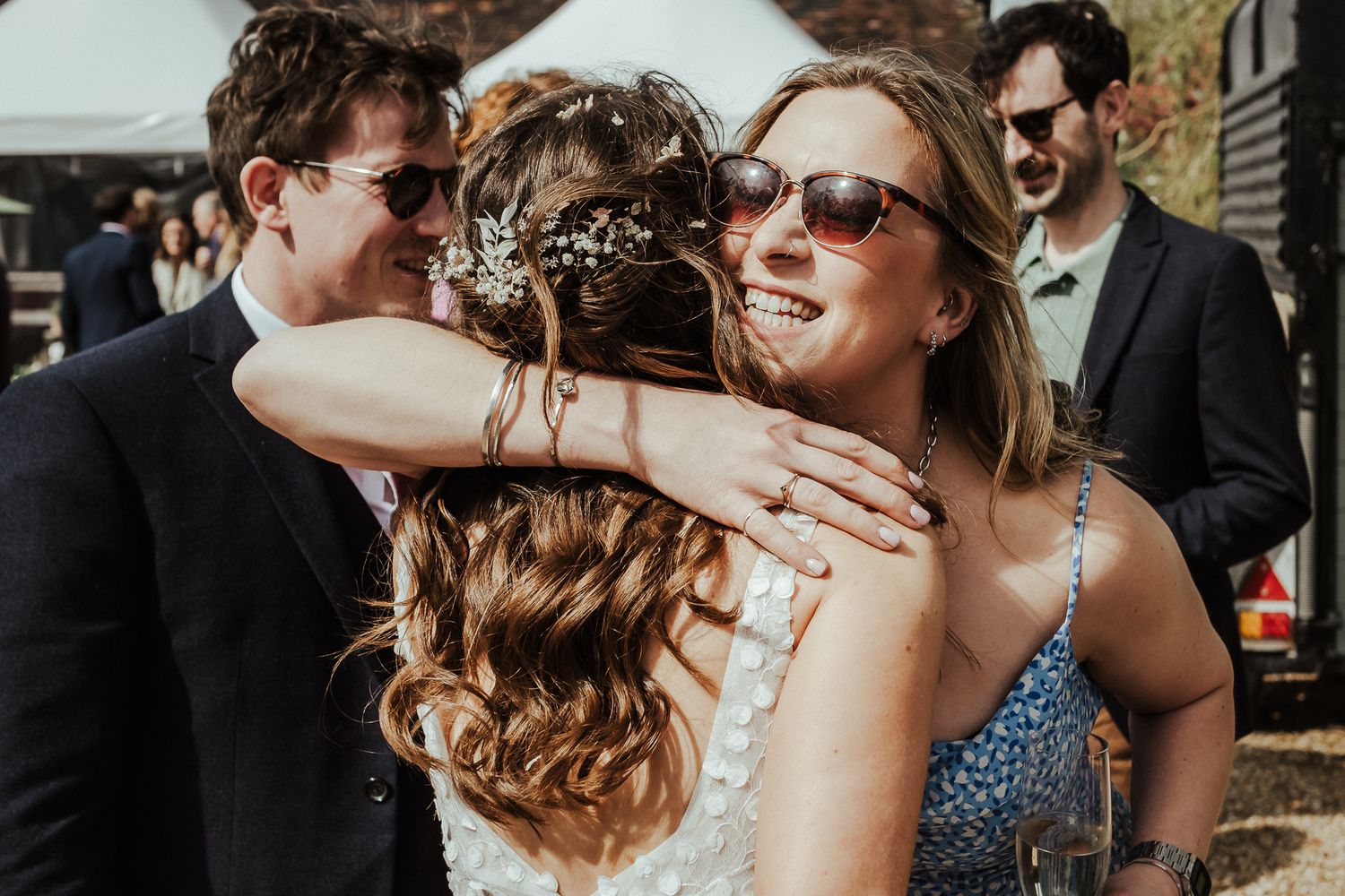 Celebratory hugs and embraces shared during outdoor wedding reception.