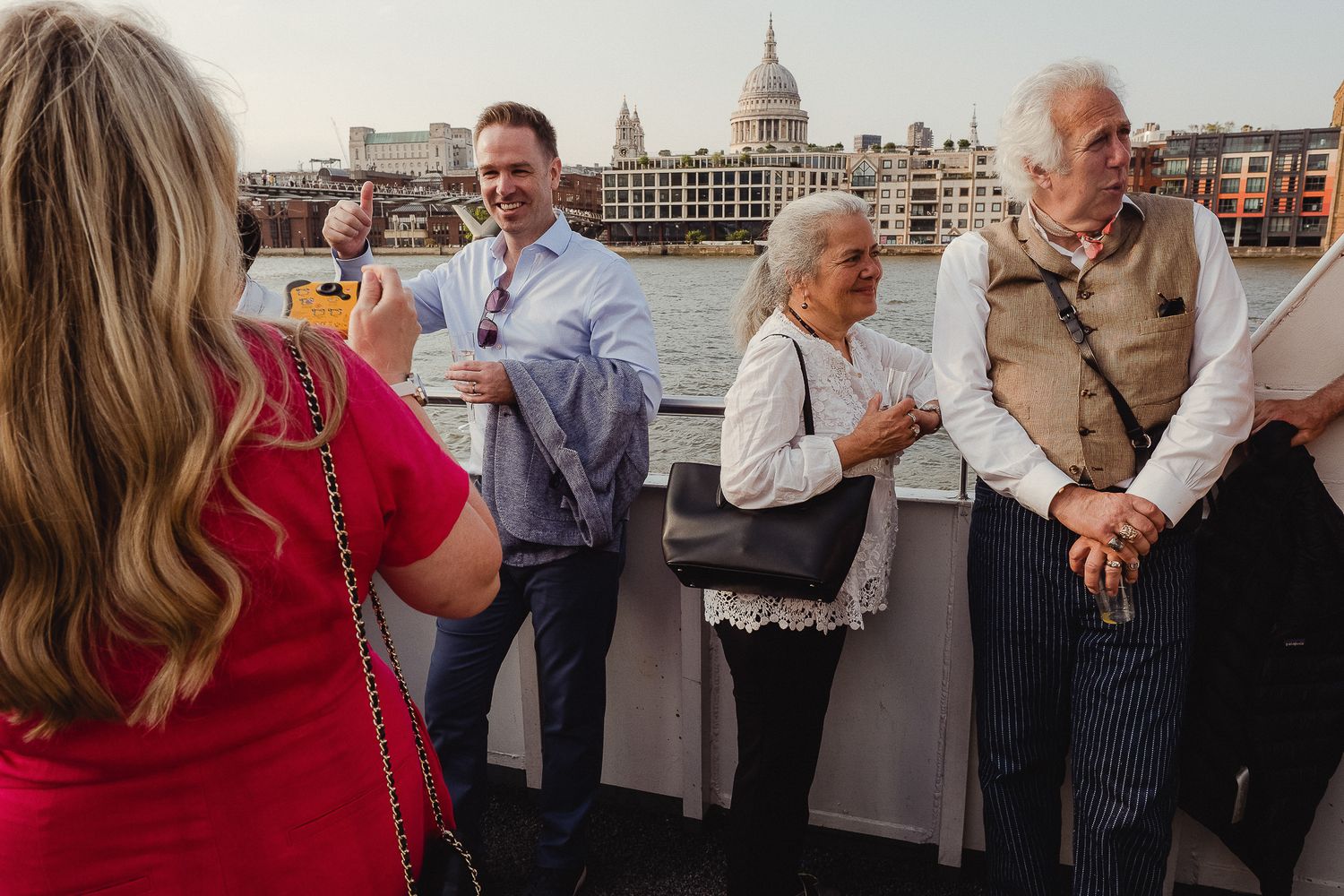 Group of people mingling and networking at an outdoor rooftop venue with St. Paul's Cathedral in background.