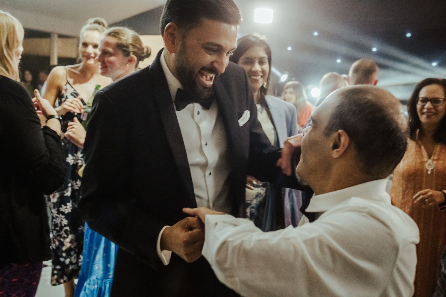 Two people share a joyful moment together on a dance floor at a formal event in evening attire.