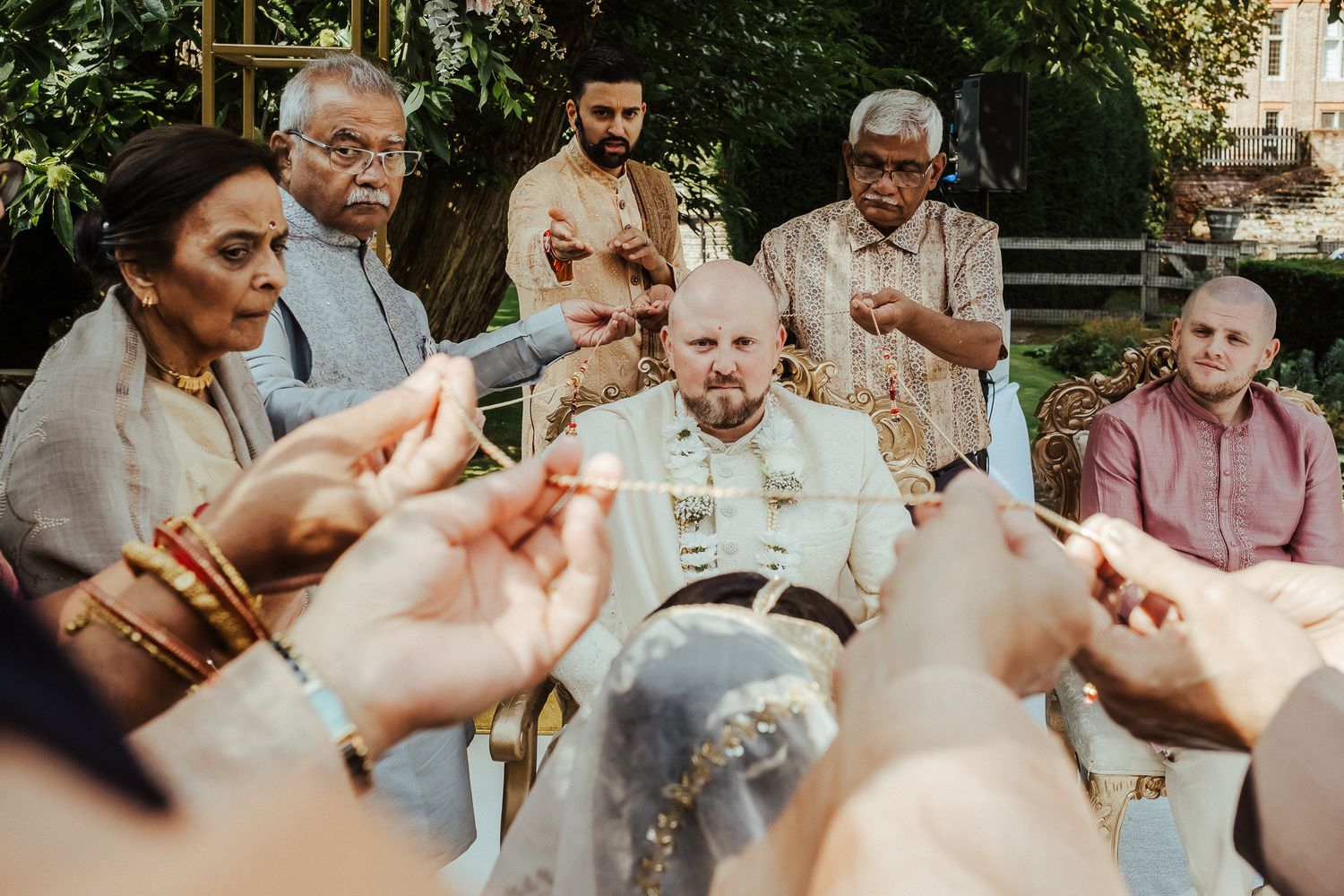 A group of elderly people gather outdoors for communion as hands reach out to share bread during a religious ceremony.