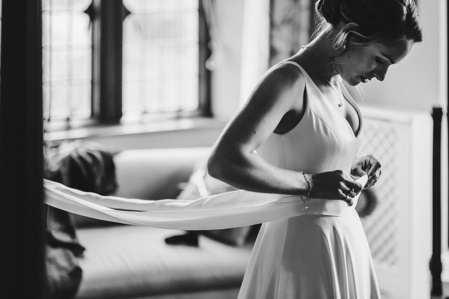 Elegant bride in white dress adjusting details during wedding preparations.