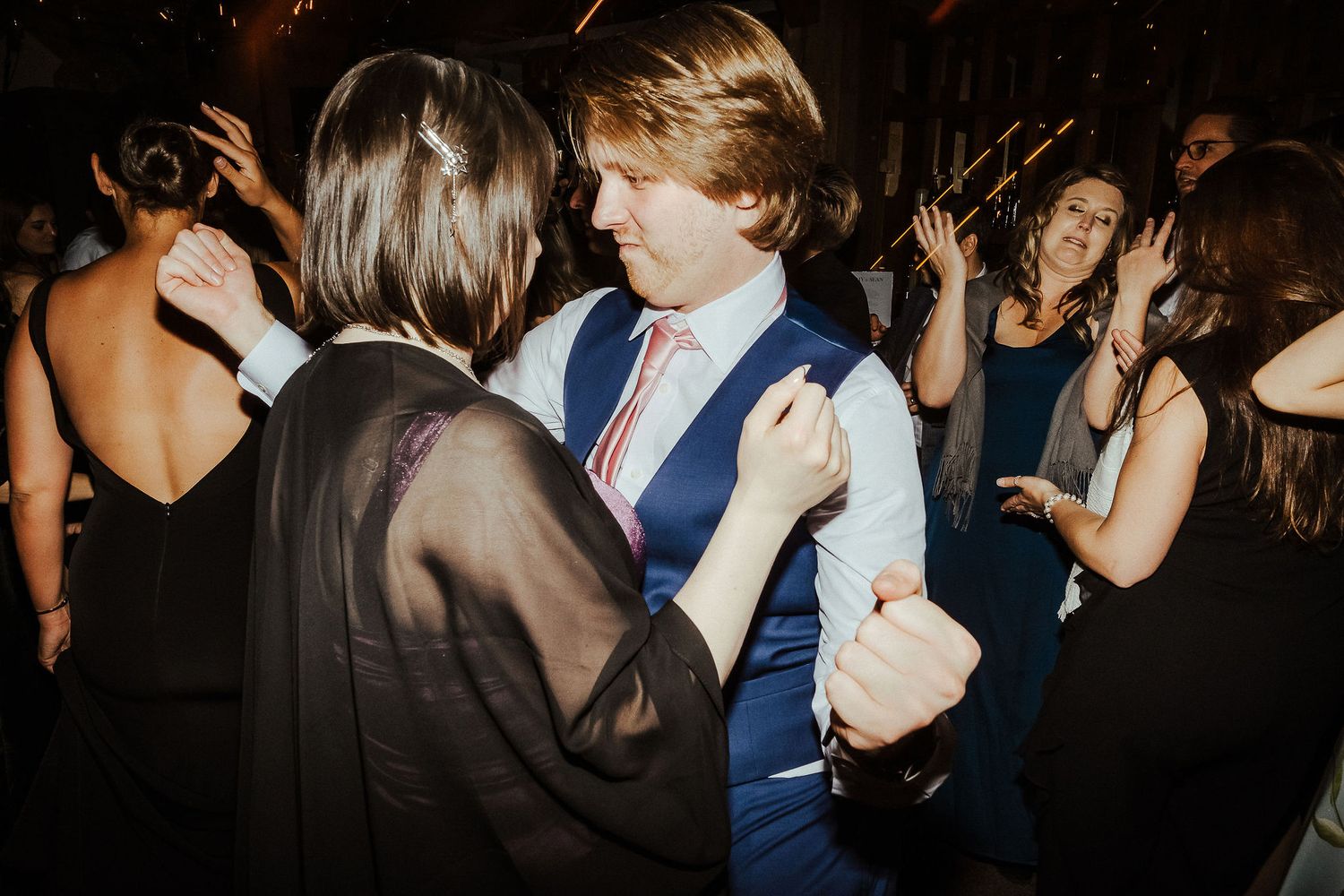 Guests dancing together at an evening celebration with dark ambient lighting.