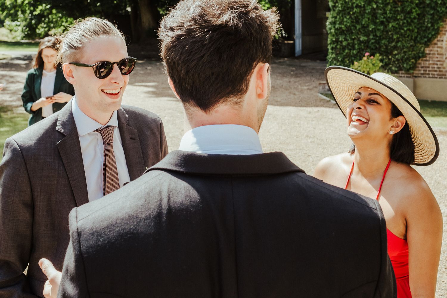 Guests sharing laughs during sunny outdoor wedding celebration.
