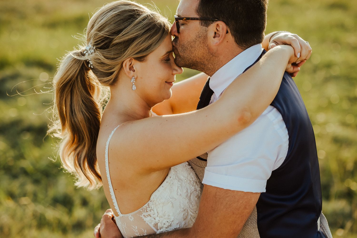 Couple embraces in warm sunset light during intimate wedding portrait session.