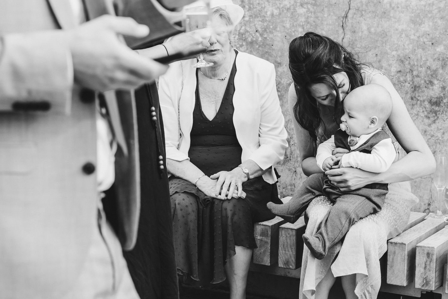 Black and white candid photo of guests at informal wedding gathering.