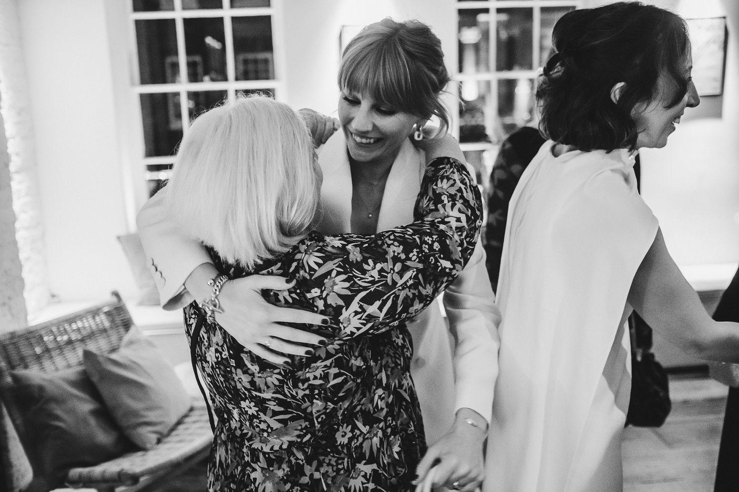 Candid black and white reception photos showing guests celebrating and embracing.