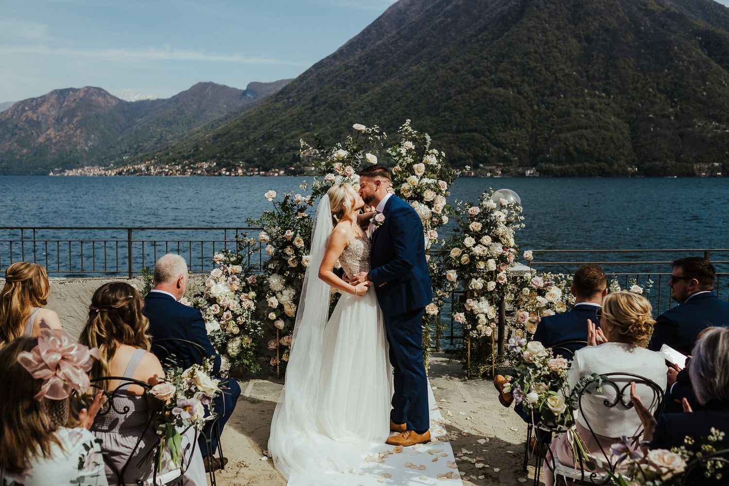 A wedding ceremony on a lakeside terrace with mountain views and floral arch decorations.