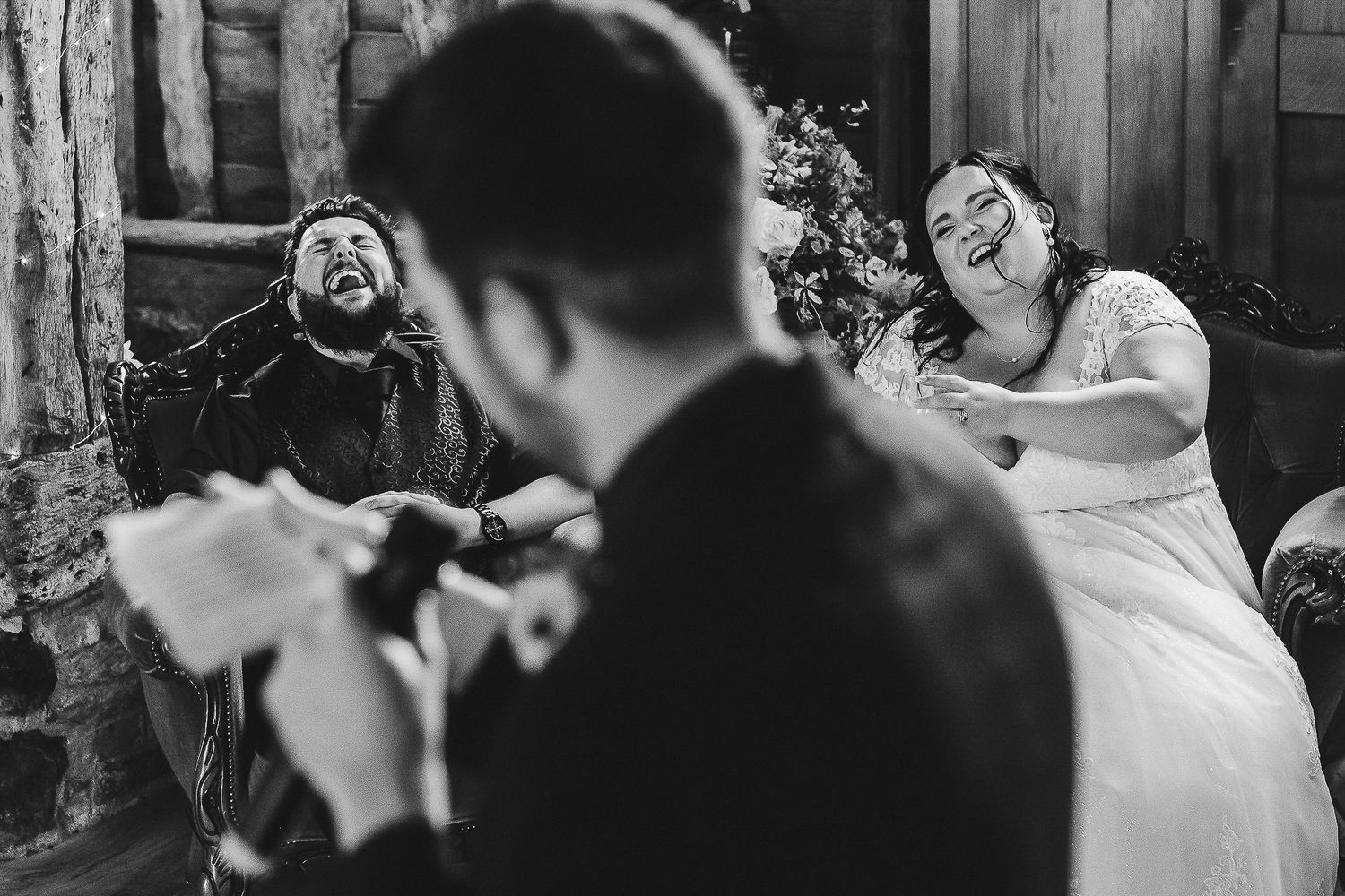 Black and white photo of guests laughing during wedding entertainment.