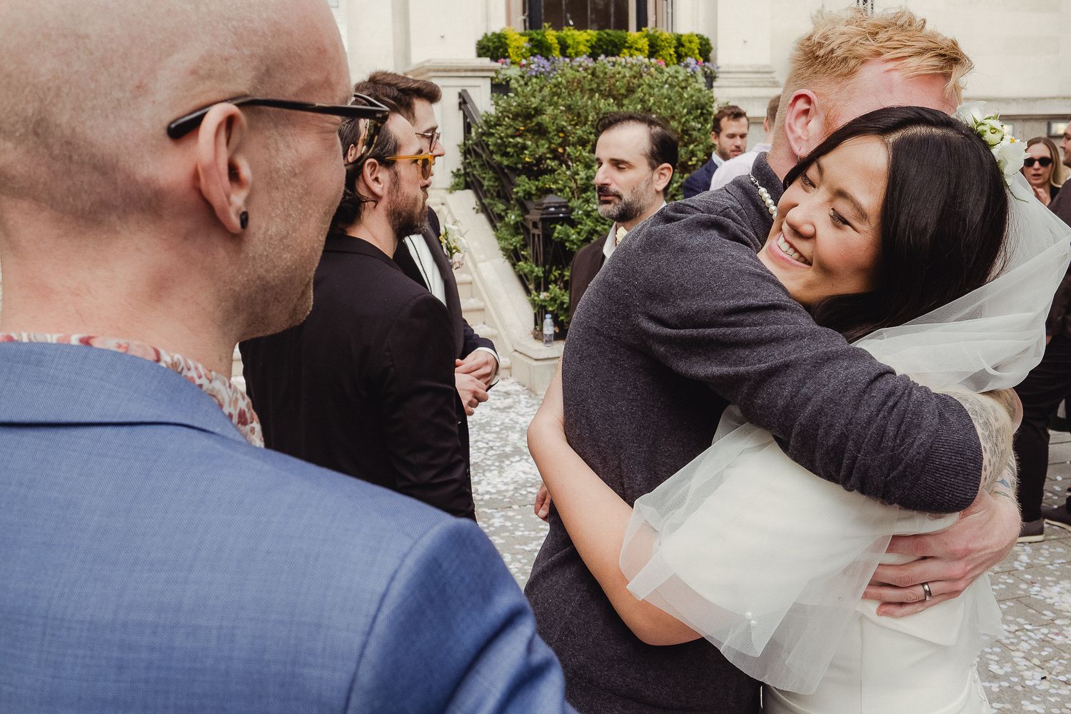 Wedding guests share emotional embraces and congratulations in an outdoor celebration setting.