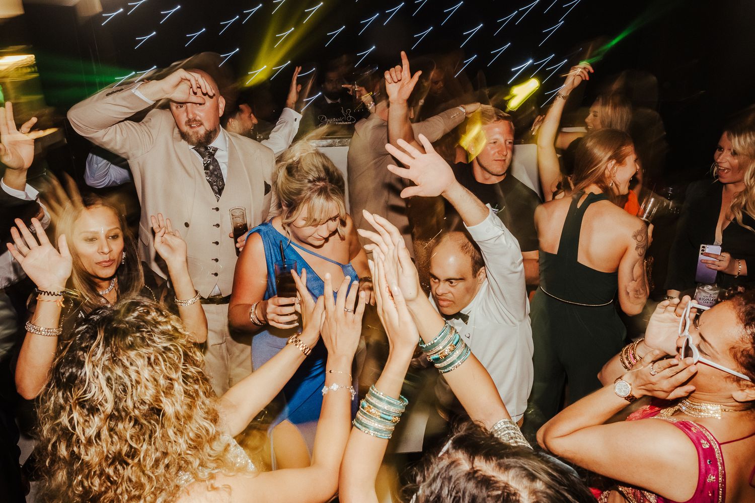 A crowd of people dancing and celebrating at a nightclub event with energetic lighting and atmosphere.