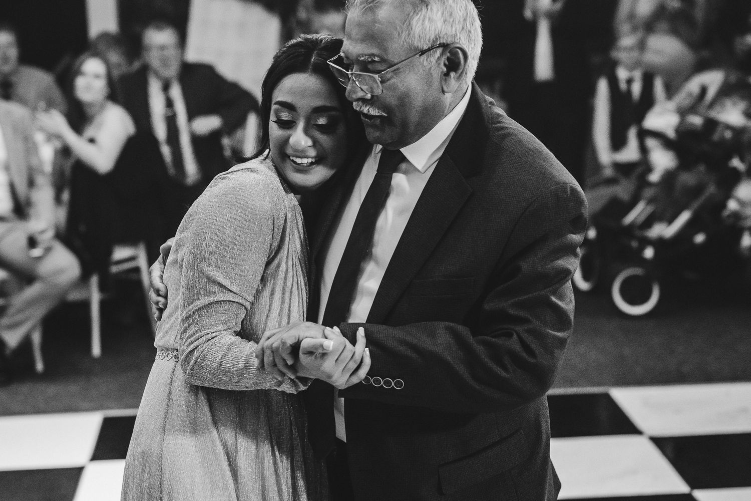 A heartwarming black and white photograph showing a tender dance moment between two people on a checkered dance floor.