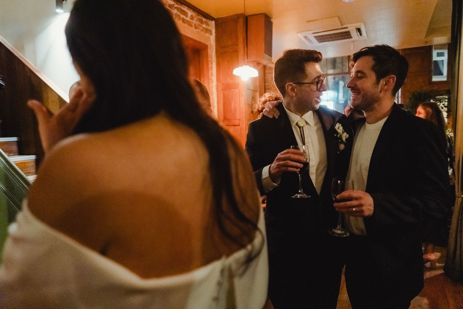 People having drinks and conversation at an elegant evening event in warm lighting.